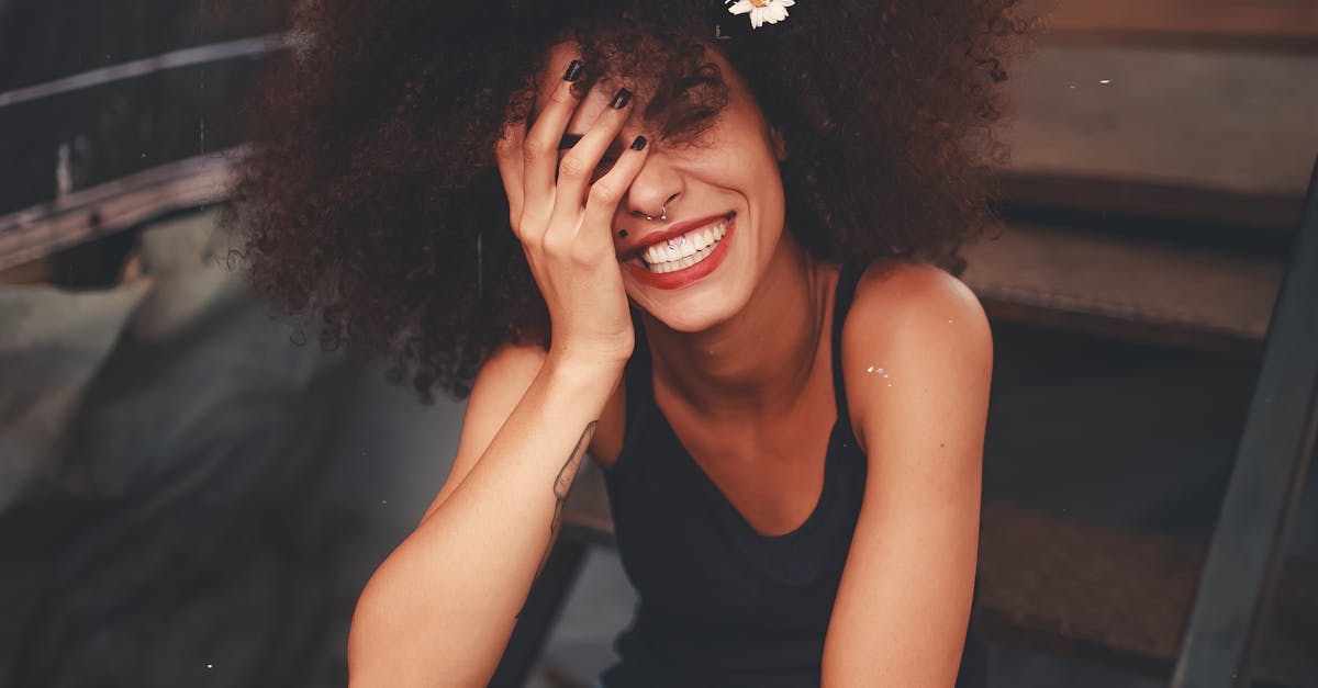 Cheerful woman wearing ripped jeans and curly hair with flower, enjoying a sunny day outdoors.